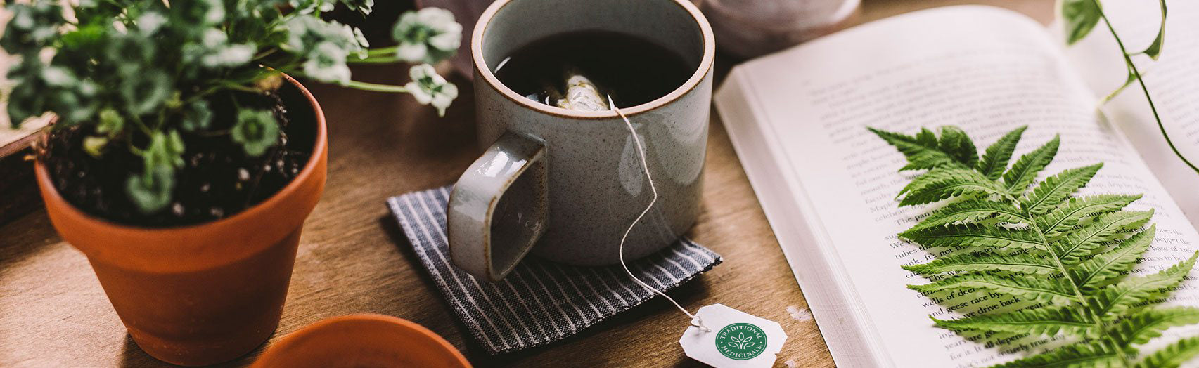 Cup of steeping tea next to open book