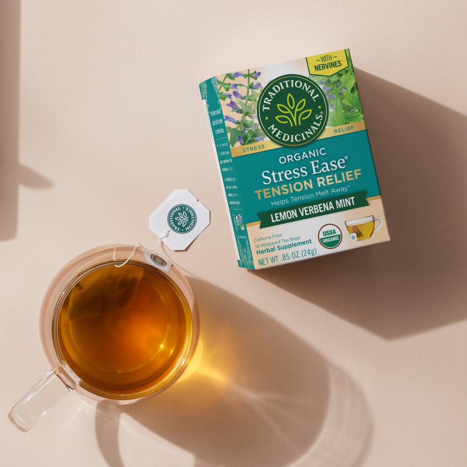 Box of Stress Ease® Tension Relief Tea with a cup of lemon verbena mint tea on a beige surface, providing peaceful moments. View 2