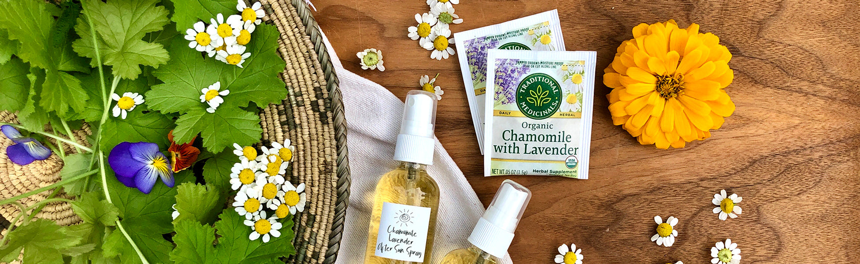 Chamomile with Lavender After Sun Spray in glass bottles surrounded by fresh herbs