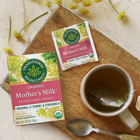 Two boxes of Traditional Medicinals Mother's Milk tea on a wooden board with a cup of tea and spoon.
