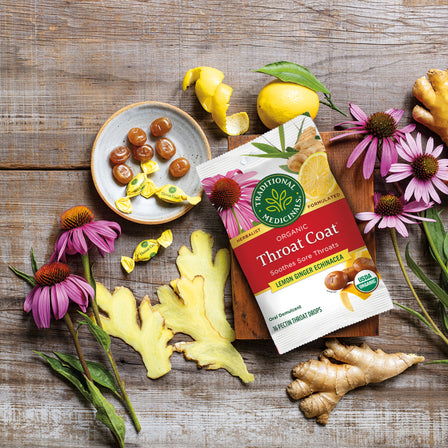 The Throat Coat® Lemon Ginger Echinacea Lozenges, 30ct are elegantly displayed on a wooden surface and offer soothing support for sore throats.