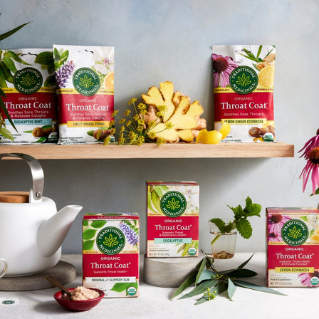 various Traditional Medicinals throat drops  on the shelf with lemon slices, eucalyptus, herbs and flowers around.